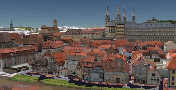 Panorama einer historischen Stadt mit dicht gedrängten roten Ziegeldächern, bunten Häusern und spitzen Kirchtürmen; im Hintergrund erstreckt sich eine lange Festungs- oder Schlossanlage über die Skyline.