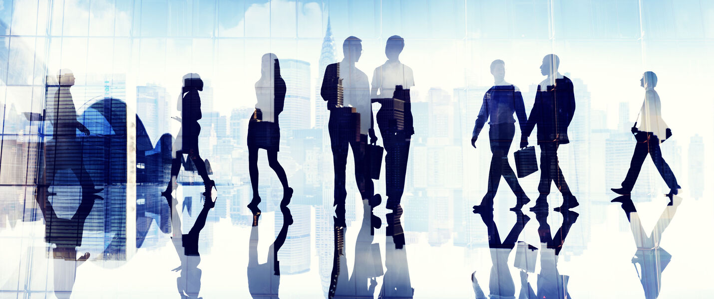 Mehrere Silhouetten von Geschäftsleuten gehen durch eine helle, gläserne Lobby; der glänzende Boden reflektiert ihre Umrisse vor einer städtischen Skyline.