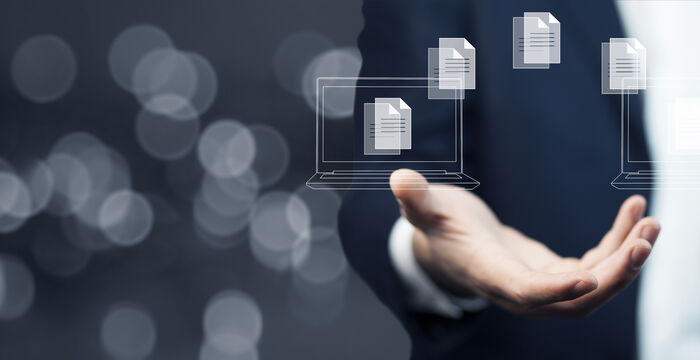 Eine Person im Anzug streckt die Hand aus, über der Hand schweben transparente Dokumente oder Dateien, Symbol für digitalen Dateiaustausch oder Cloud-Übertragung.